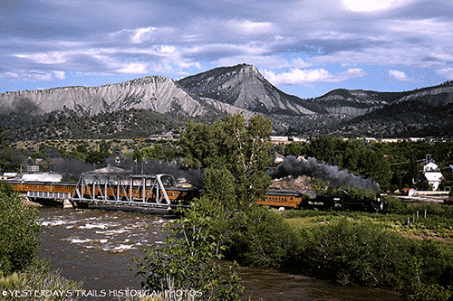 This panoramic view features the Durango & Silverton excursion train underway on a trip between the towns of Durango & Silverton Colorado in this image from July 1965. 